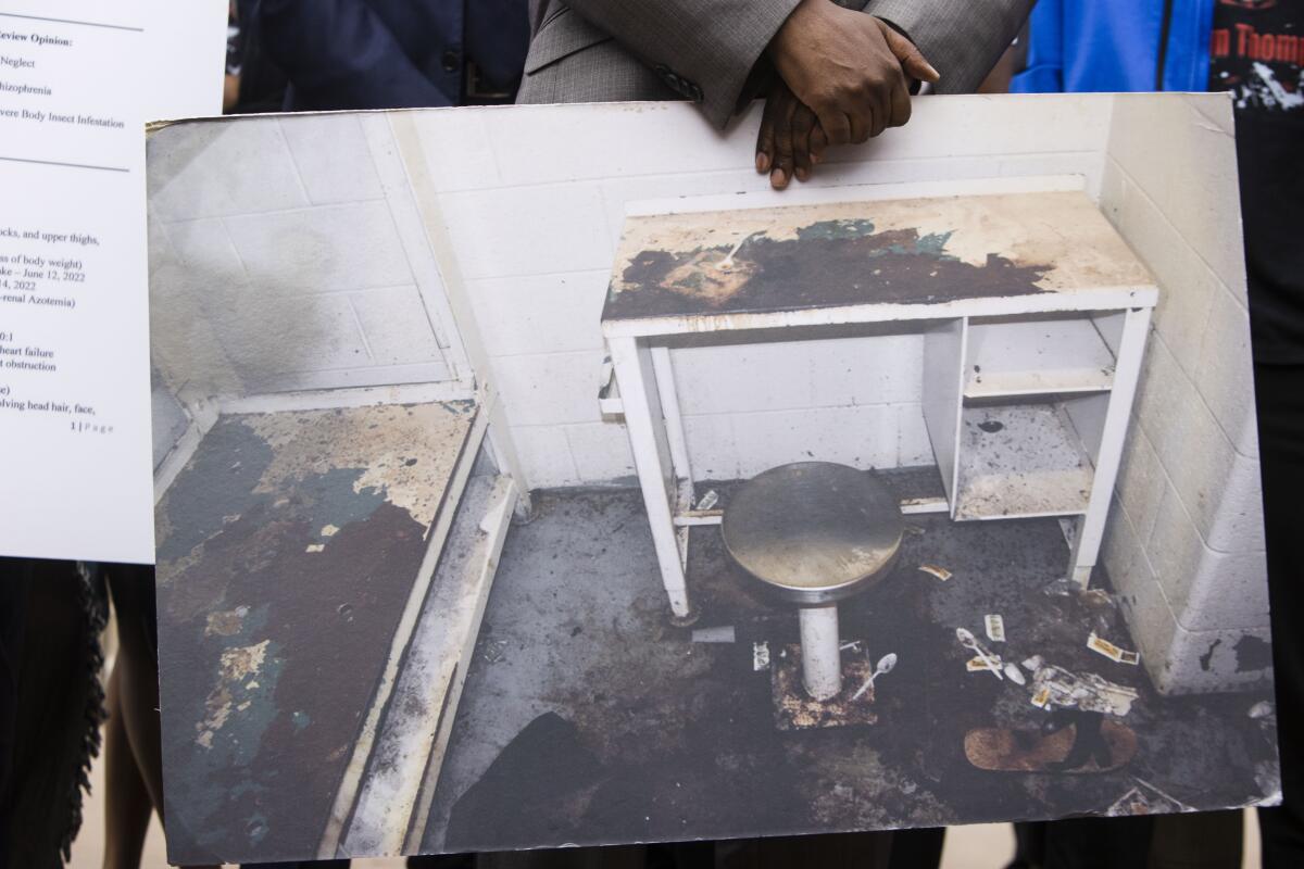 A man holding a photo of a filthy jail cell