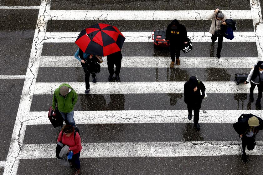 EL SEGUNDO-CA-JANUARY 22, 2024: Travelers arrive at LAX in the rain on January 22, 2024. The strongest in a series of three storms is sliding into the Southland today. (Christina House / Los Angeles Times)