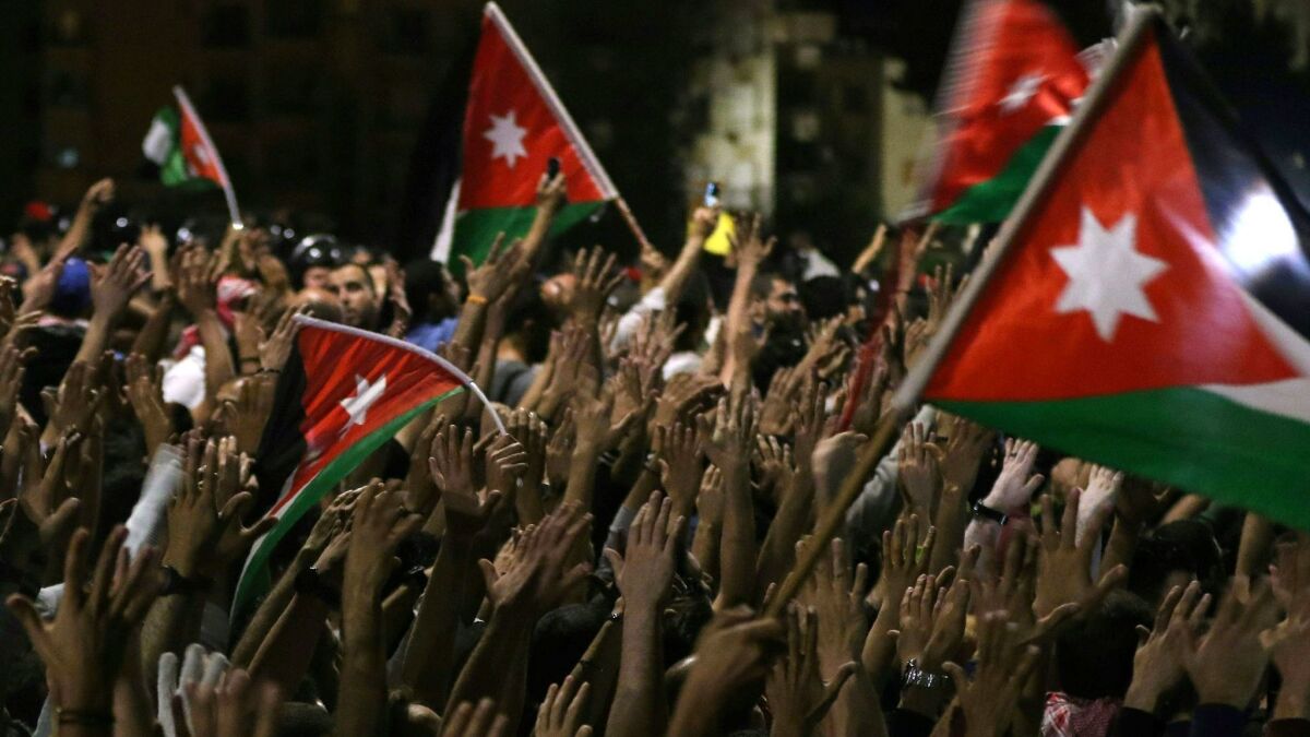 Protesters raise their hands and wave flags near members of the gendarmerie and security forces during a demonstration outside the prime minister's office in Amman, Jordan's capital, late on June 3, 2018.