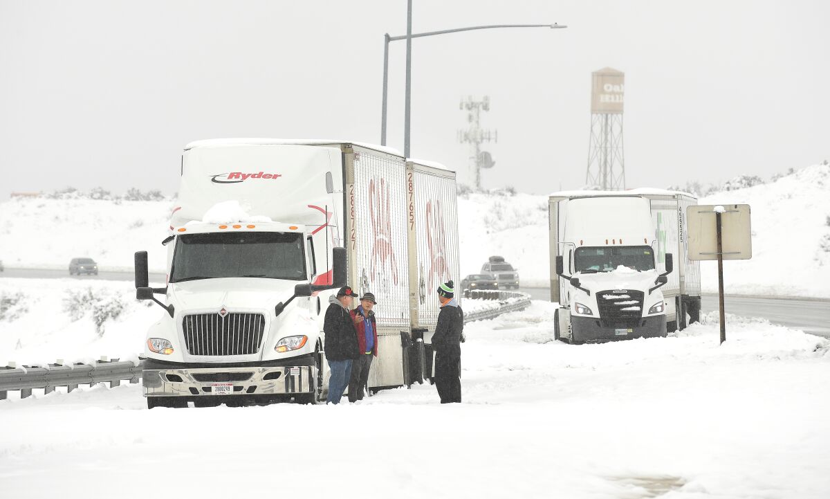 Truckers stand along Interstate 15 in the Cajon Pass on Thursday waiting to be towed. 