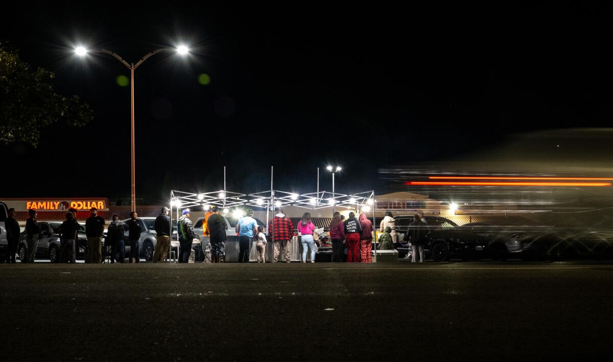 A crowd forms at a taco stand.