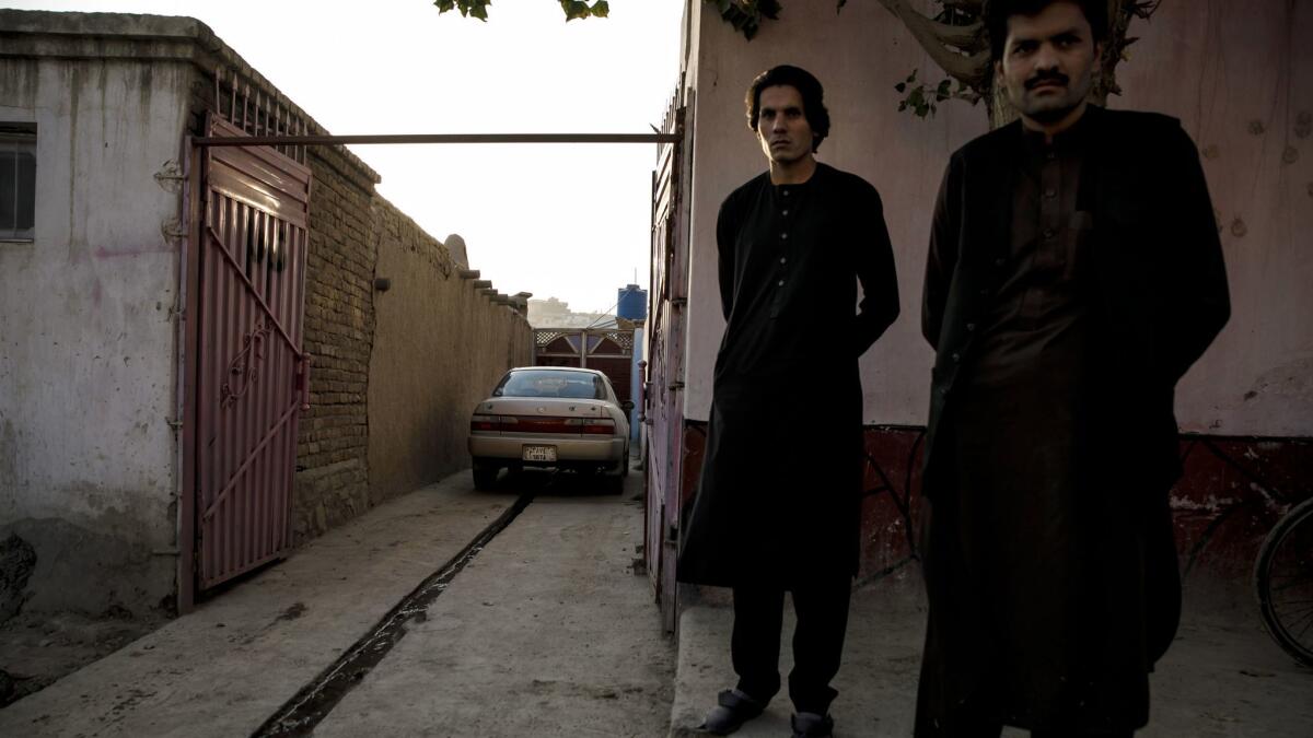 Almar Habibzai’s brothers Sangar, left, and Seelab stand near where Almar was killed outside their home after he parked his Toyota Corolla when returning home from work in Kabul, Afghanistan.