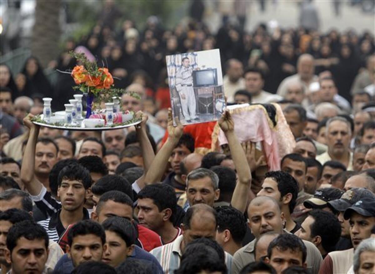 Mourners carry the coffin of Hashem Mohammed, seen in the picture, during his funeral in central Baghdad, Iraq, Wednesday, April 7, 2010. Hundreds of people are gathering for funerals after bombs ripped through apartment buildings and a market in Baghdad on Tuesday. The tray at left held aloft carries flowers and candles which will be lit at the burial. (AP Photo/Hadi Mizban)