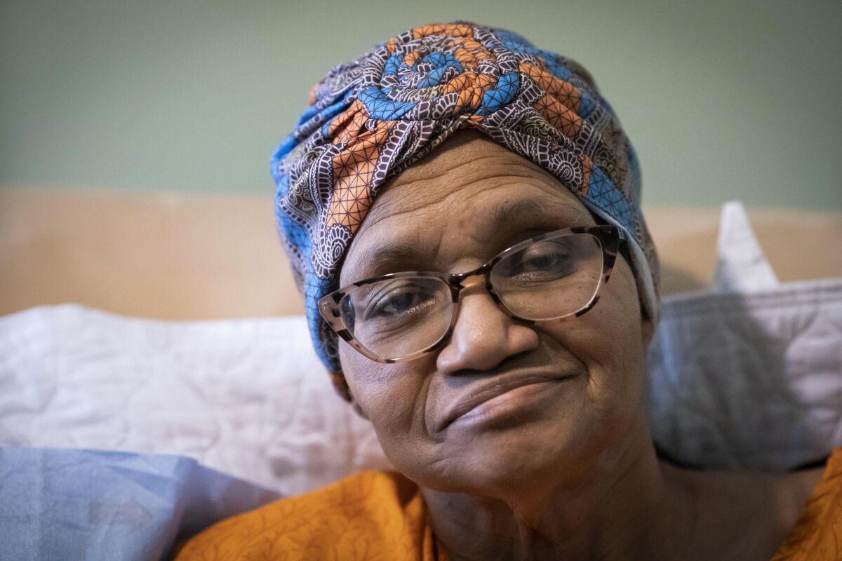 A closeup of a woman in bed wearing a colorful headwrap.