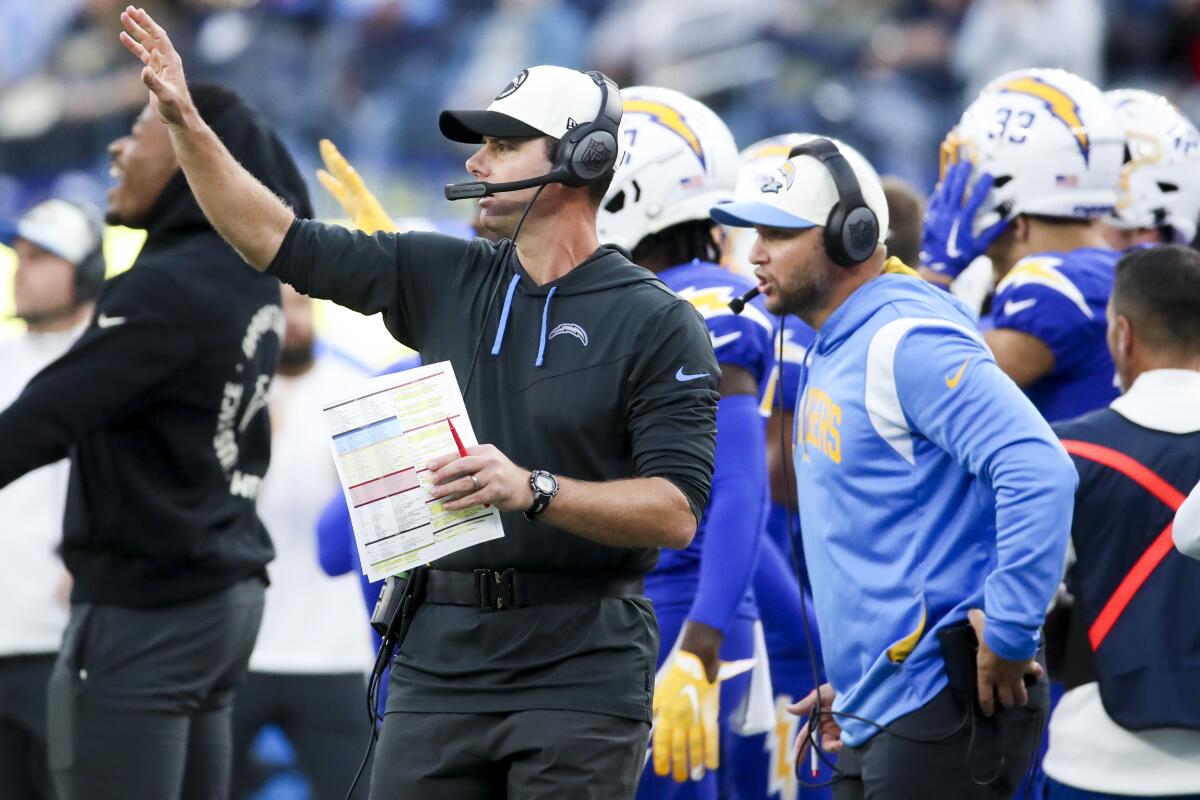 Chargers coach Brandon Staley gestures from the sideline toward players on the field.