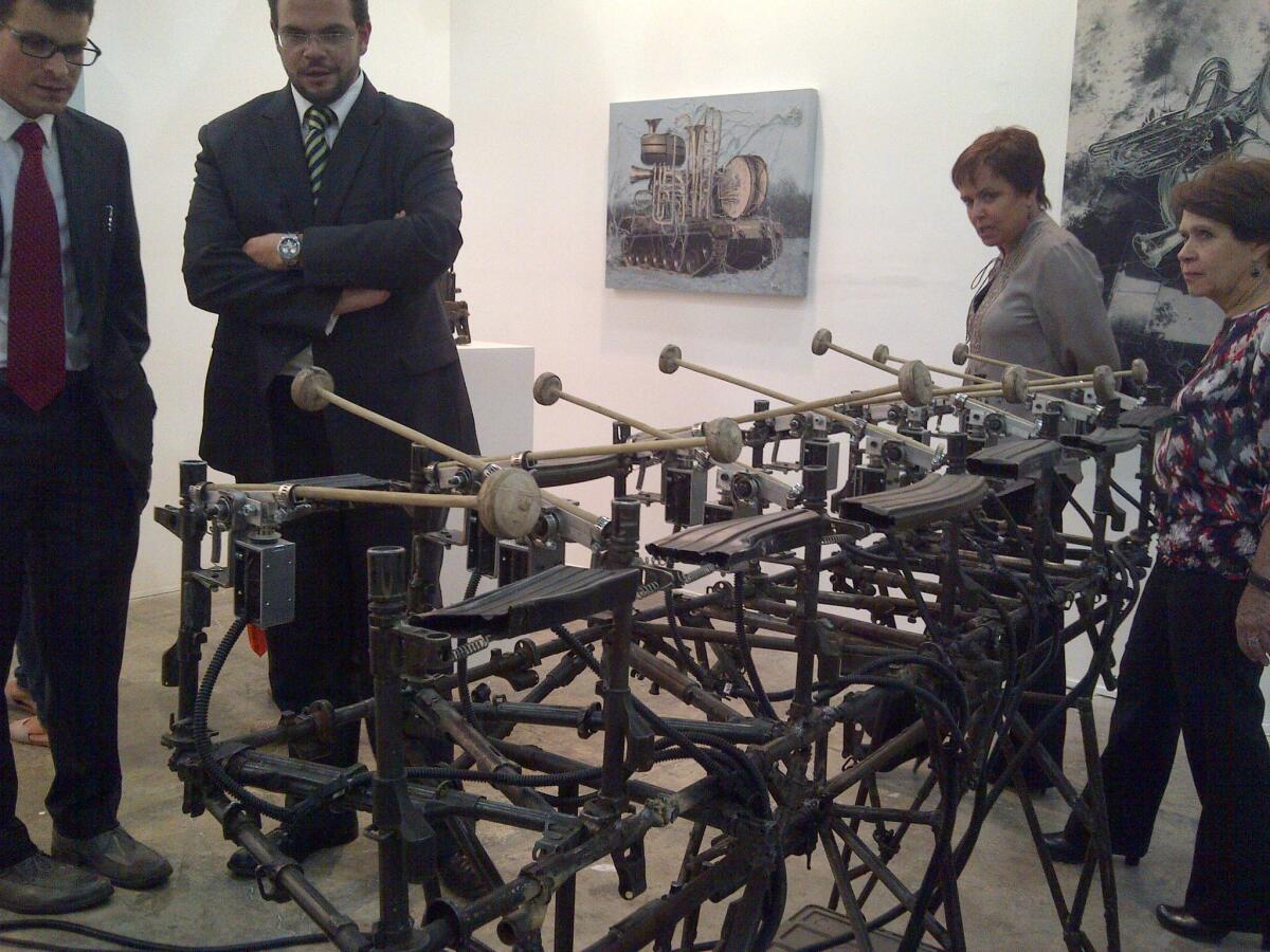 Visitors at the Zona Maco Mexico City contemporary art fair examine artist Pedro Reyes' working xylophone made out of gun parts from Mexico's drug war.