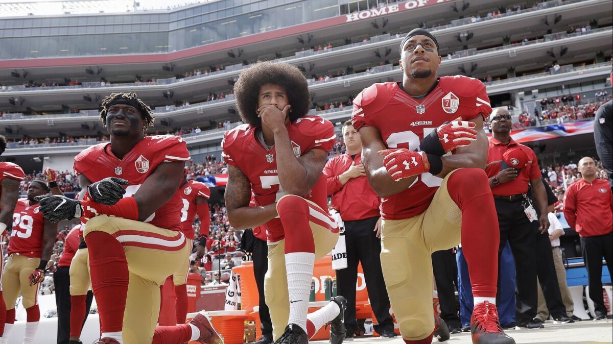 Colin Kaepernick, then-quarterback for the San Francisco 49ers, is flanked by outside linebacker Eli Harold, left, and safety Eric Reid during the national anthem before a 2016 NFL game against the Dallas Cowboys in Santa Clara.