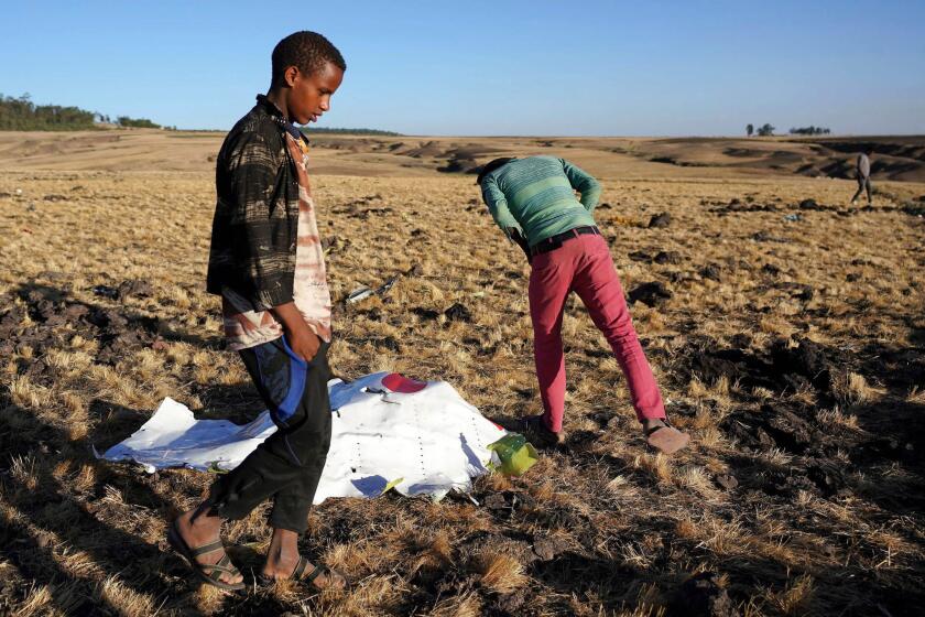 Local residents look at debris at the scene where Ethiopian Airlines Flight 302 crashed in a wheat field just outside the town of Bishoftu.