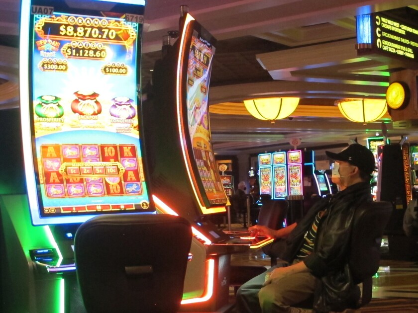 This Jan. 27, 2022, photo shows a gambler playing a slot machine at Caesars casino in Atlantic City, N.J. Figures released on April 5, by the American Gaming Association show the U.S. casino industry is off to its best two-month start in history this year, having won nearly $9 billion from gamblers in January and February. (AP Photo/Wayne Parry)