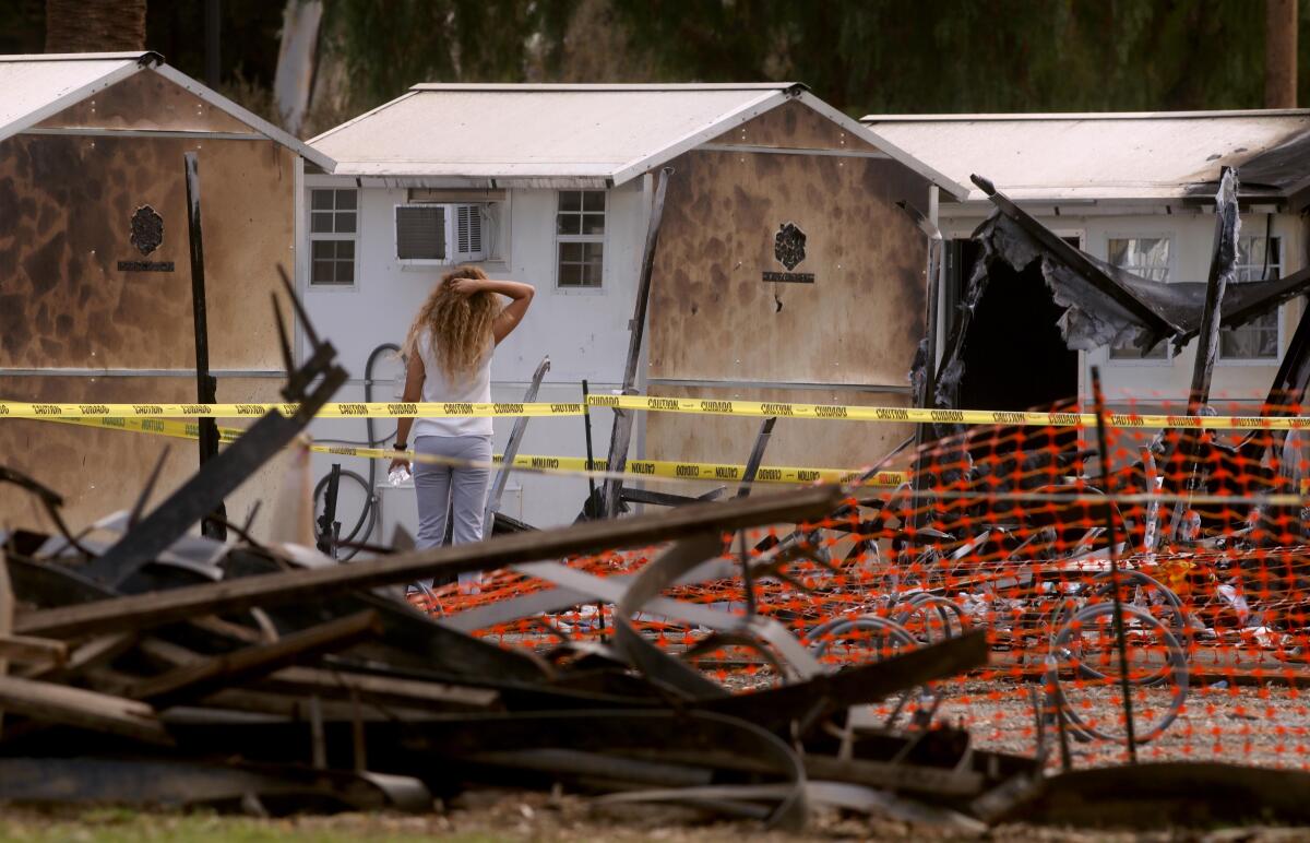 A woman looks at some of the tiny homes that were destroyed and damaged in a fire.