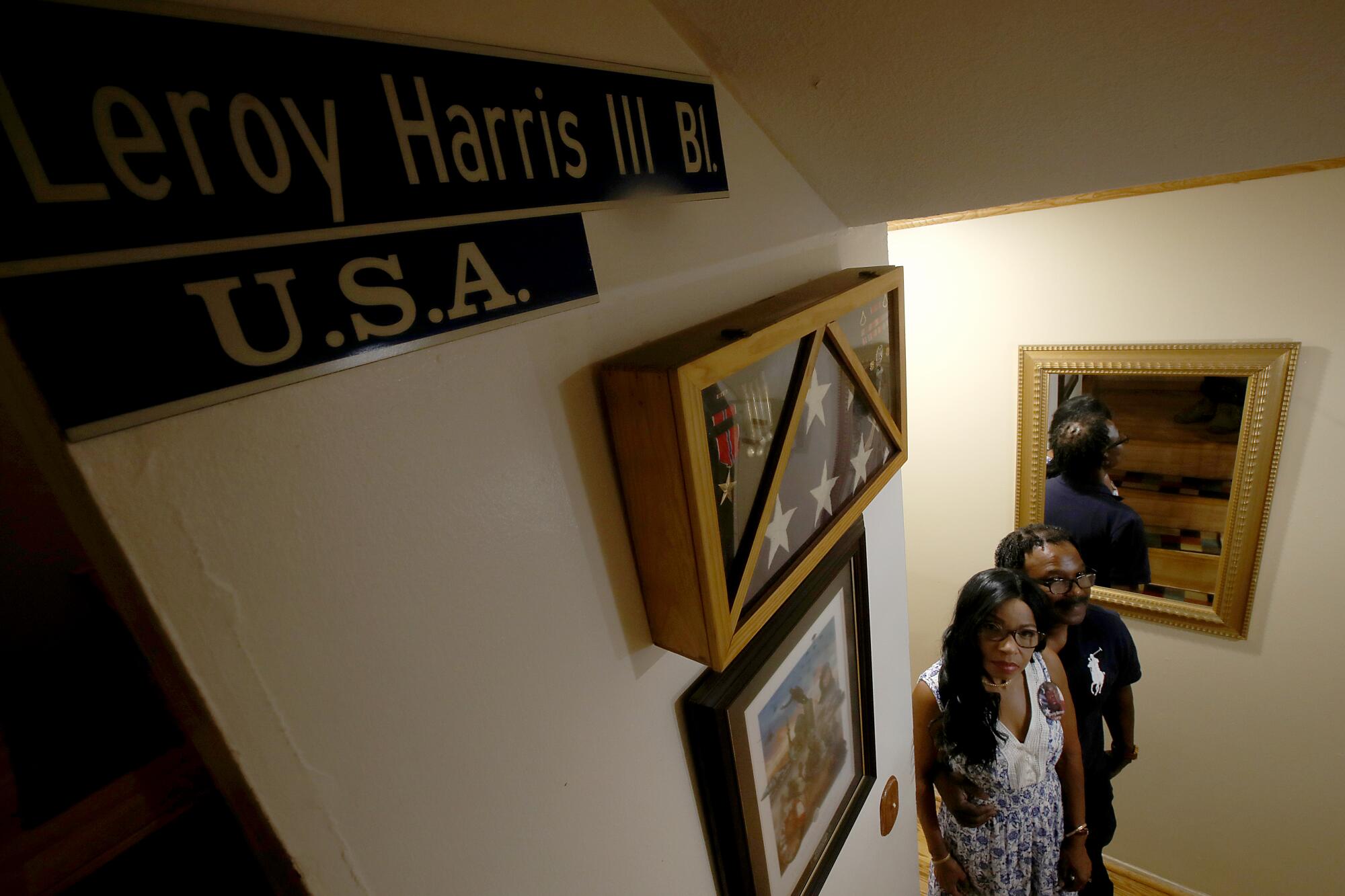 Guiselle and Leroy Harris Jr. have pictures, a flag and a sign honoring their son along their stairs 