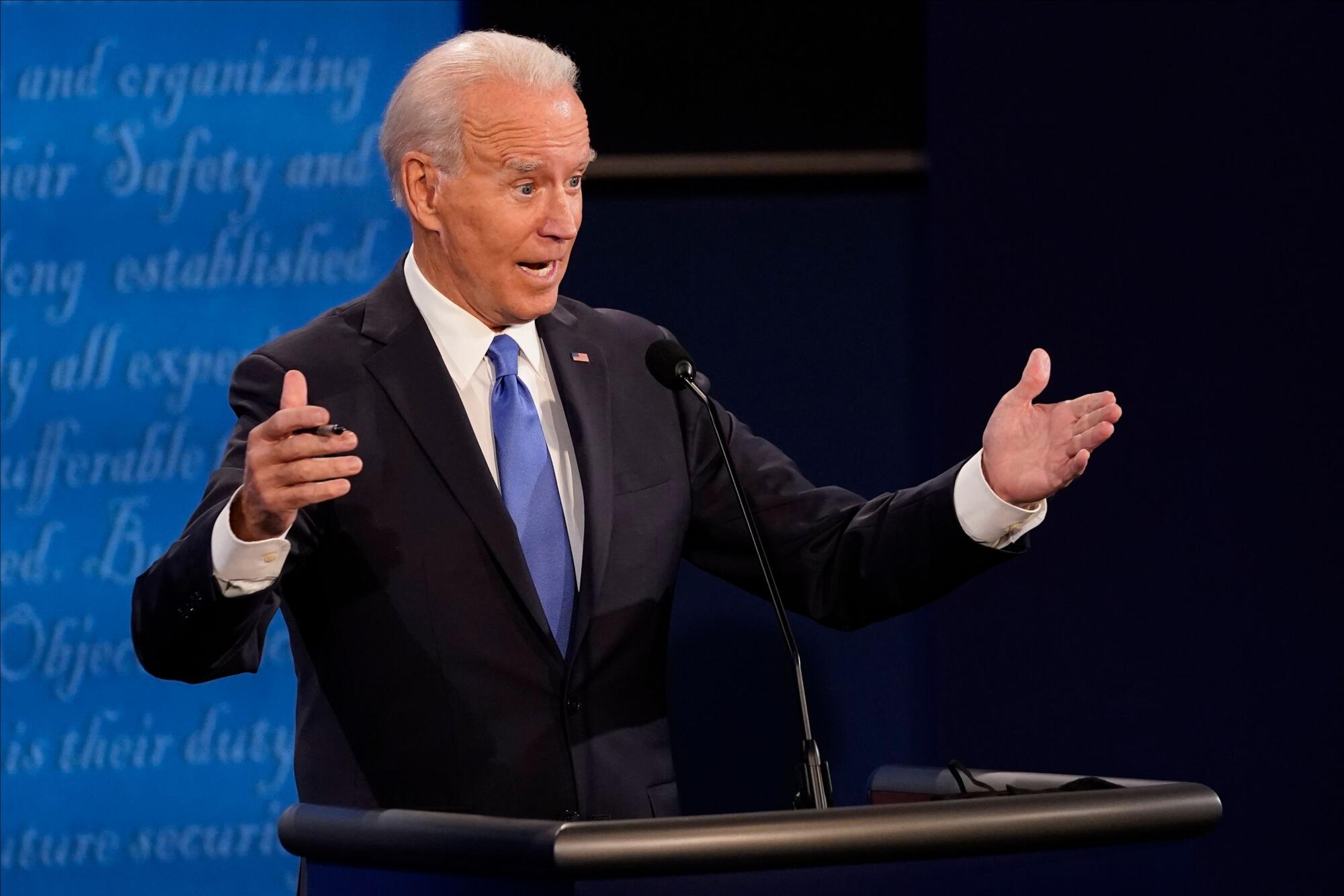 Joe Biden gestures with both hands as he speaks onstage