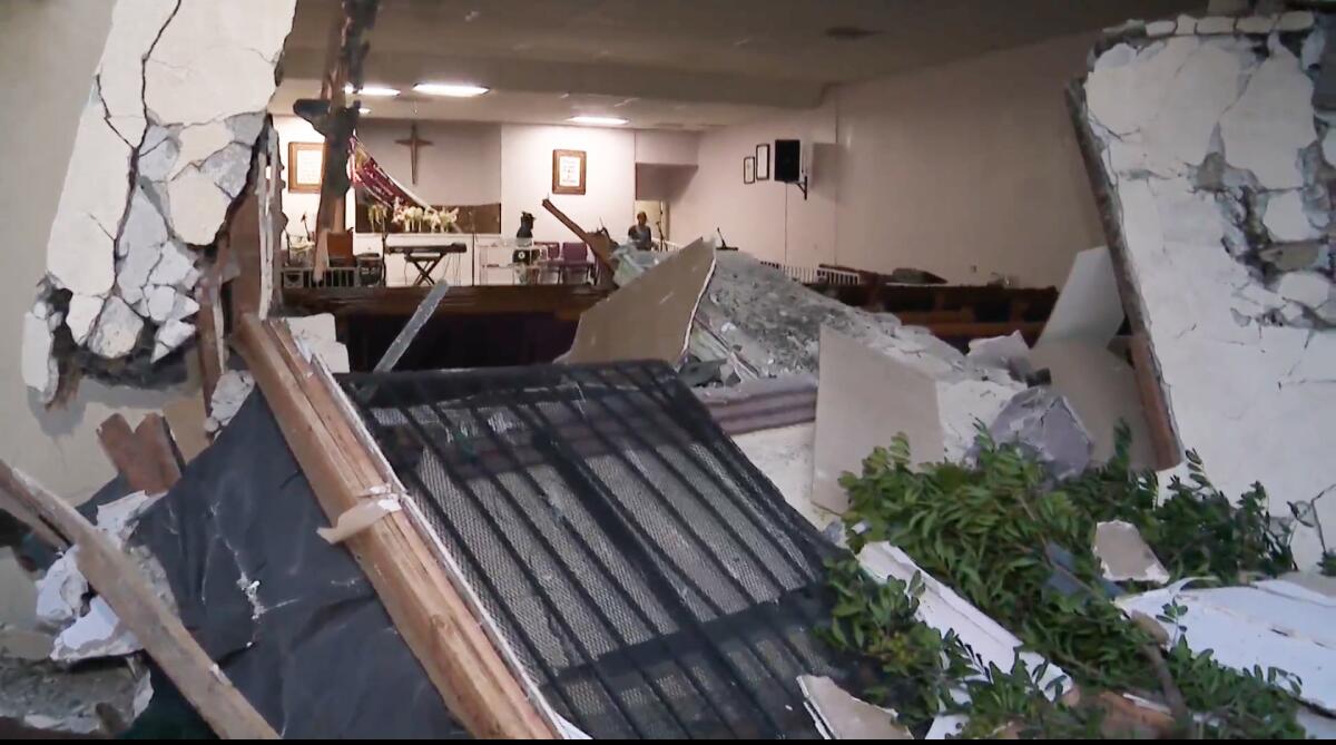 Debris and an opening in a building in the foreground and the interior of a church inside the building.