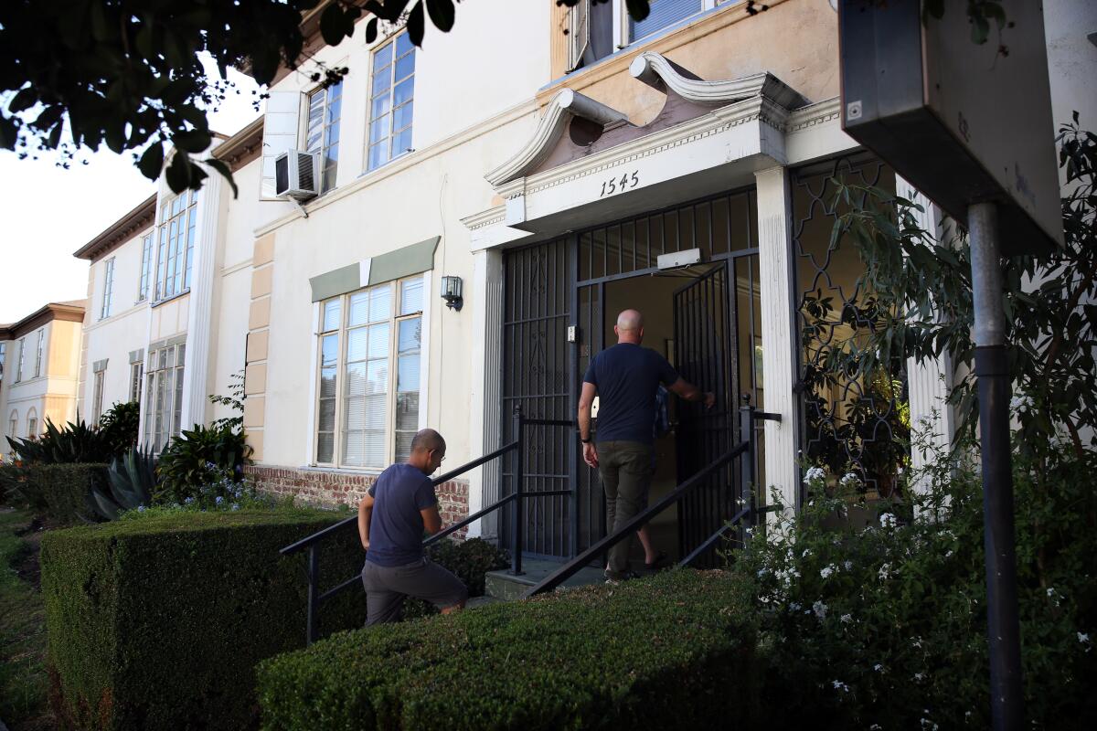 John Ramirez, left, and Darrin Wilstead walk through their Hollywood apartment complex to talk to fellow tenants about concerns with a proposed agreement with the building owner.