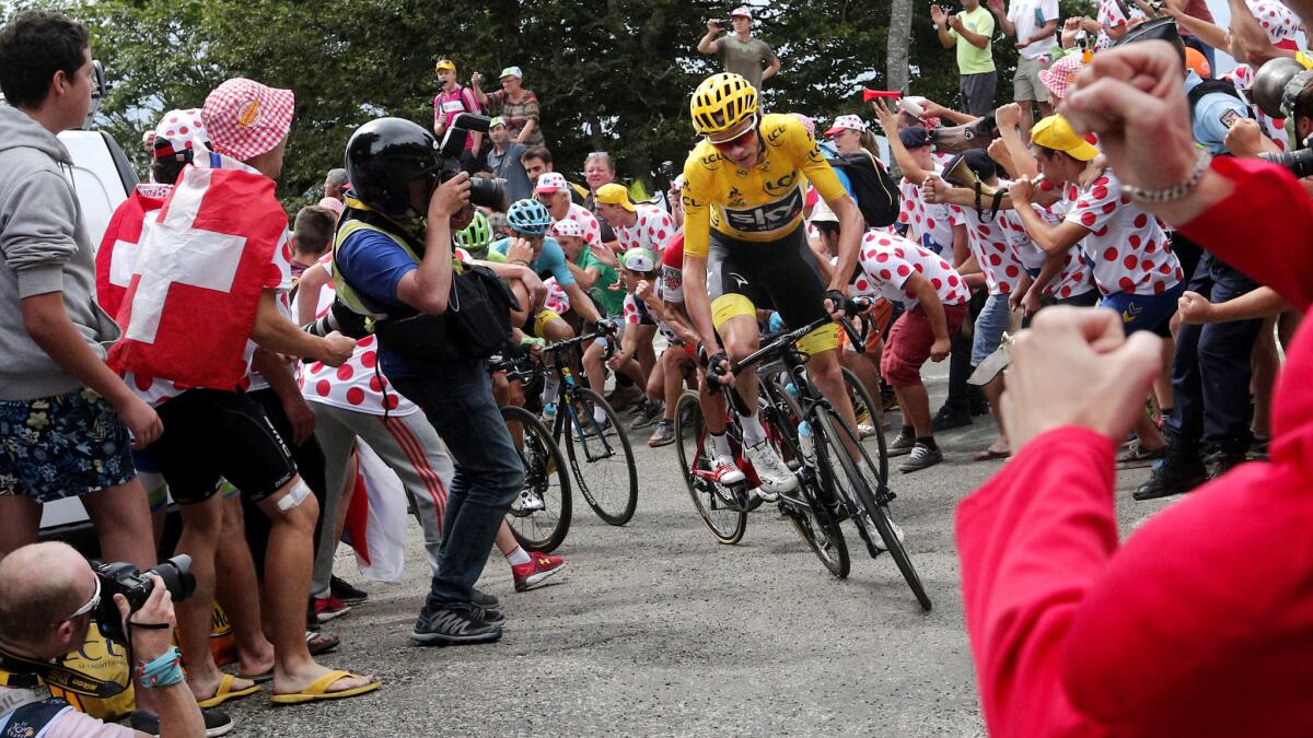 Chris Froome climbs a narrow path through spectators during the ninth stage of the Tour de France on Sunday.