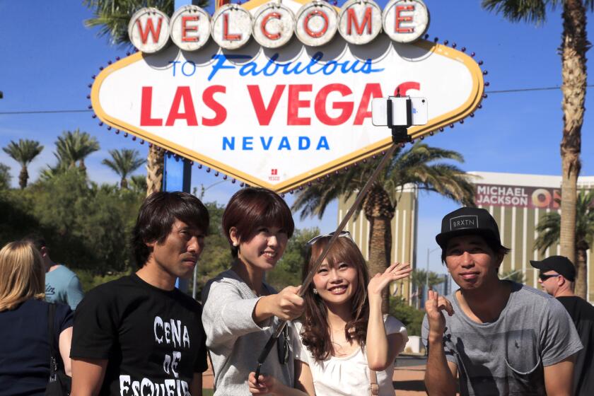 Tourists crowd around the iconic Las Vegas sign on Las Vegas Boulevard to pose for a selfie.