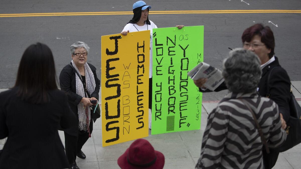 A man who would not be identified holds signs outside City Hall after groups for and against temporary homeless shelters spilled out of a City Council meeting.