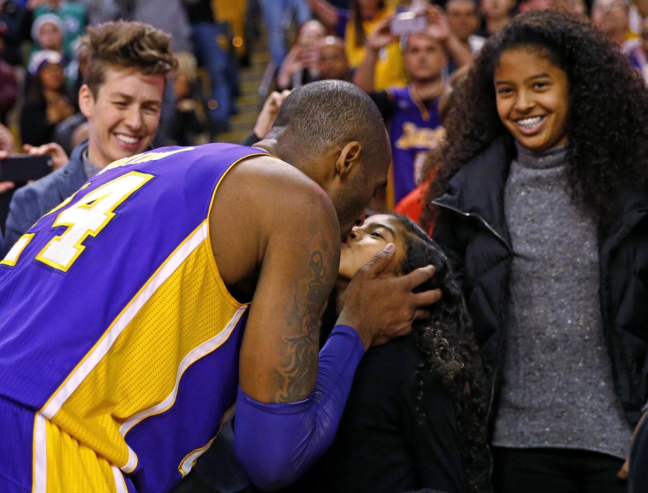 Los Angeles Lakers' Kobe Bryant kisses his daughter Gianna as his other daughter, Natalia, watches after Bryant played his last regular season game in Boston, a 112-104 win over the Boston Celtics in an NBA basketball game in Boston Wednesday, Dec. 30, 2015. (AP Photo/Winslow Townson)