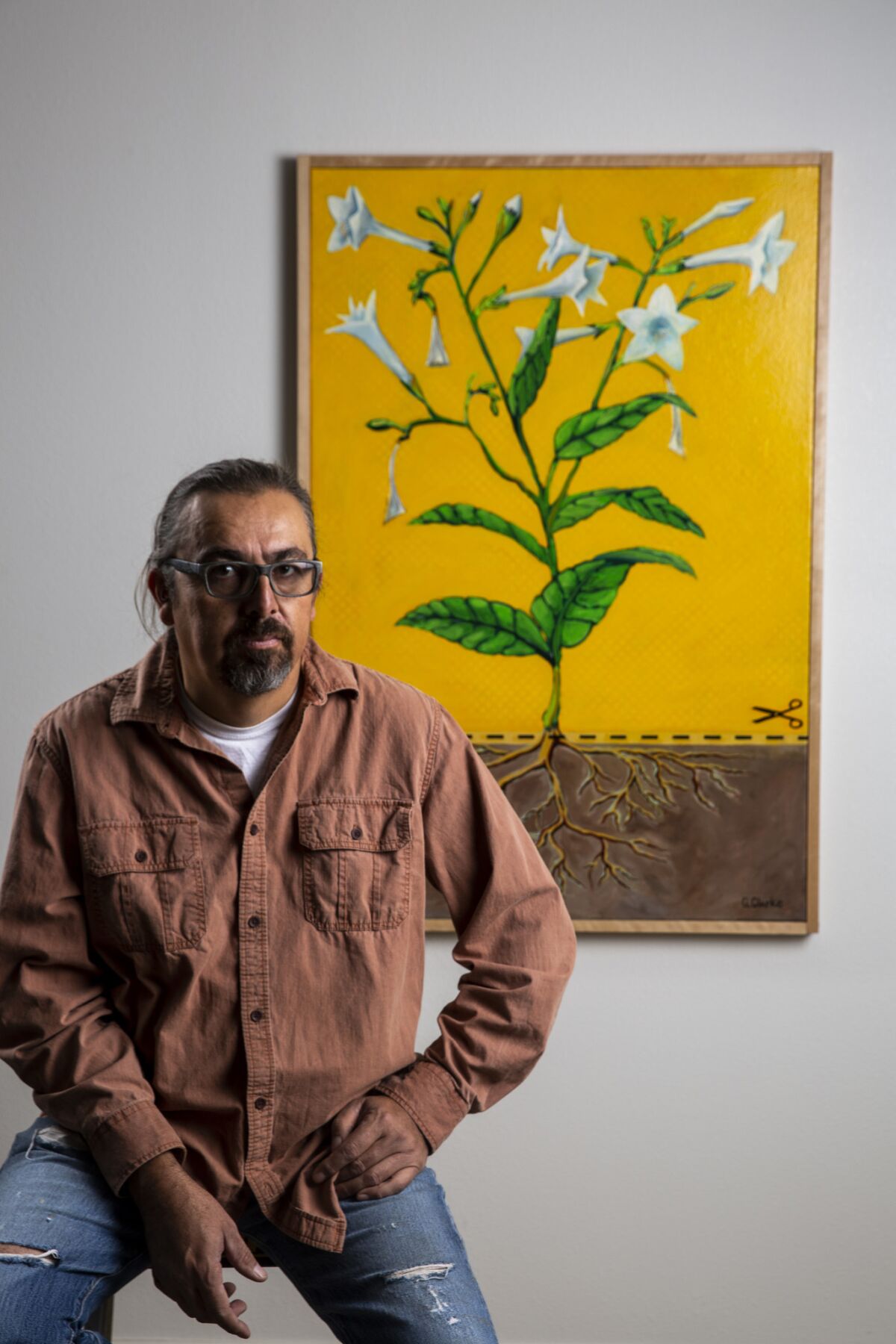 Cahuilla artist Gerald Clarke Jr. poses for a portrait with his artwork titled "Disenrollment," at his home on the Cahuilla Indian reservation on Monday, Nov. 26, 2018 in Anza, Calif.
