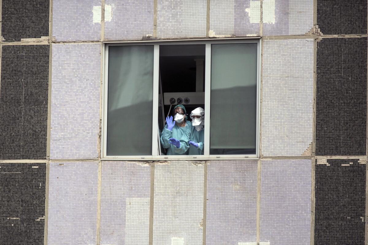 Medical workers wearing protective masks gesture from a hospital in Madrid on March 18.