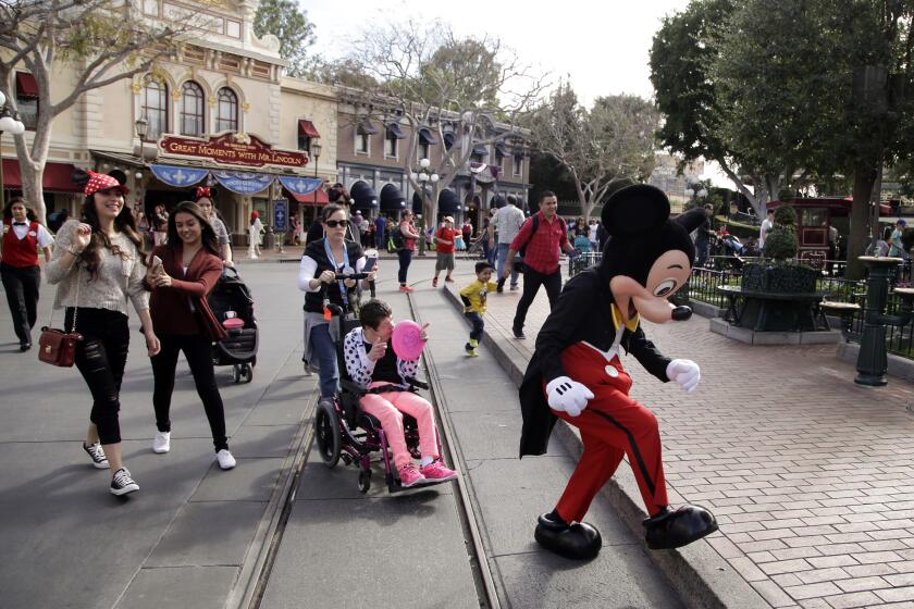 FILE - Visitors follow Mickey Mouse for photos at Disneyland, Jan. 22, 2015, in Anaheim, Calif. Disneyland performers who help bring Mickey Mouse, Cinderella and other beloved characters to life at the Southern California resort chose to unionize following a three-day vote culminating on Saturday, May 18, 2024. (AP Photo/Jae C. Hong, File)