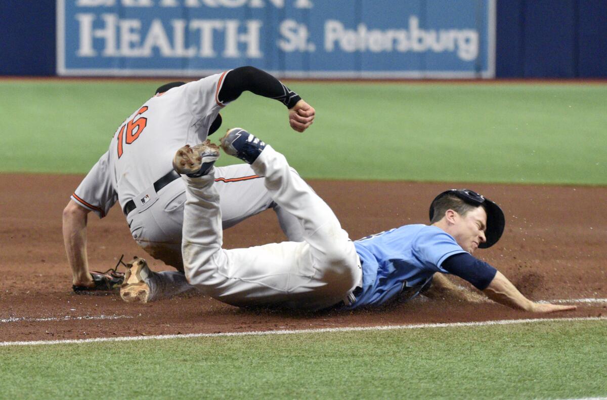 Tampa Bay Rays' Joey Wendle, right, dives into first base as Baltimore Orioles' Trey Mancini (16) makes the put out during the fourth inning of a baseball game Sunday, June 13, 2021, in St. Petersburg, Fla. (AP Photo/Steve Nesius)
