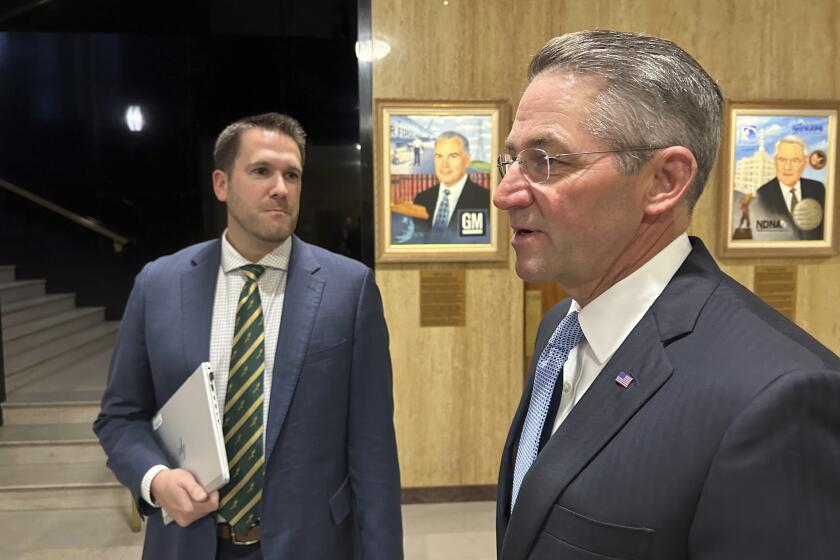 North Dakota Secretary of State Michael Howe, at left, and Attorney General Drew Wrigley, at right, converse with State Treasurer Thomas Beadle, unseen, before a meeting at the state Capitol in Bismarck, N.D., on Friday, Sept. 29, 2023. Howe and Wrigley are named in a federal lawsuit filed by supporters of a proposed ballot measure for congressional age limits in North Dakota. The measure backers seek to use out-of-state petition circulators for their initiative push. (AP Photo/Jack Dura)