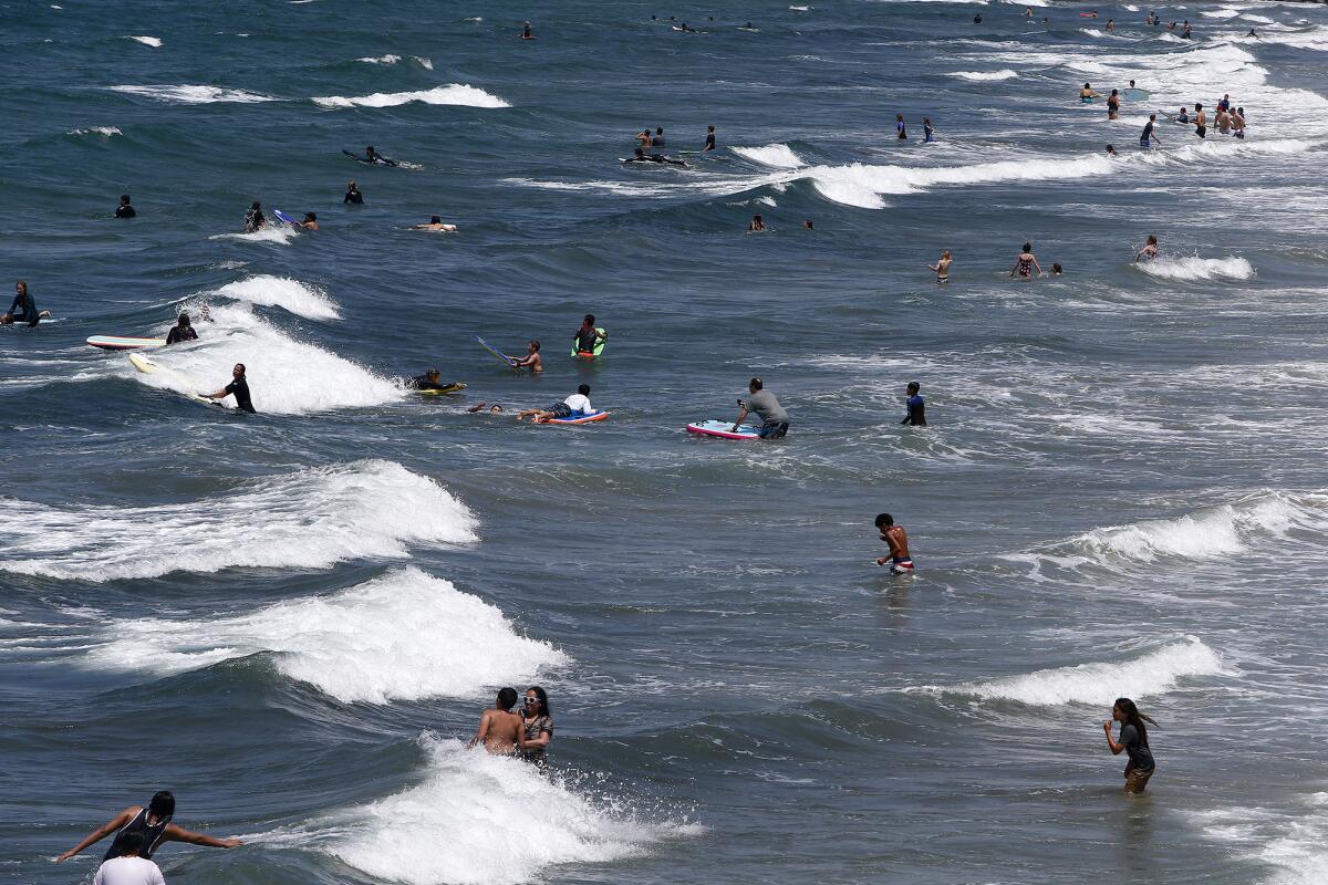 Beach-goers enjoy several swells as they play in the ocean.