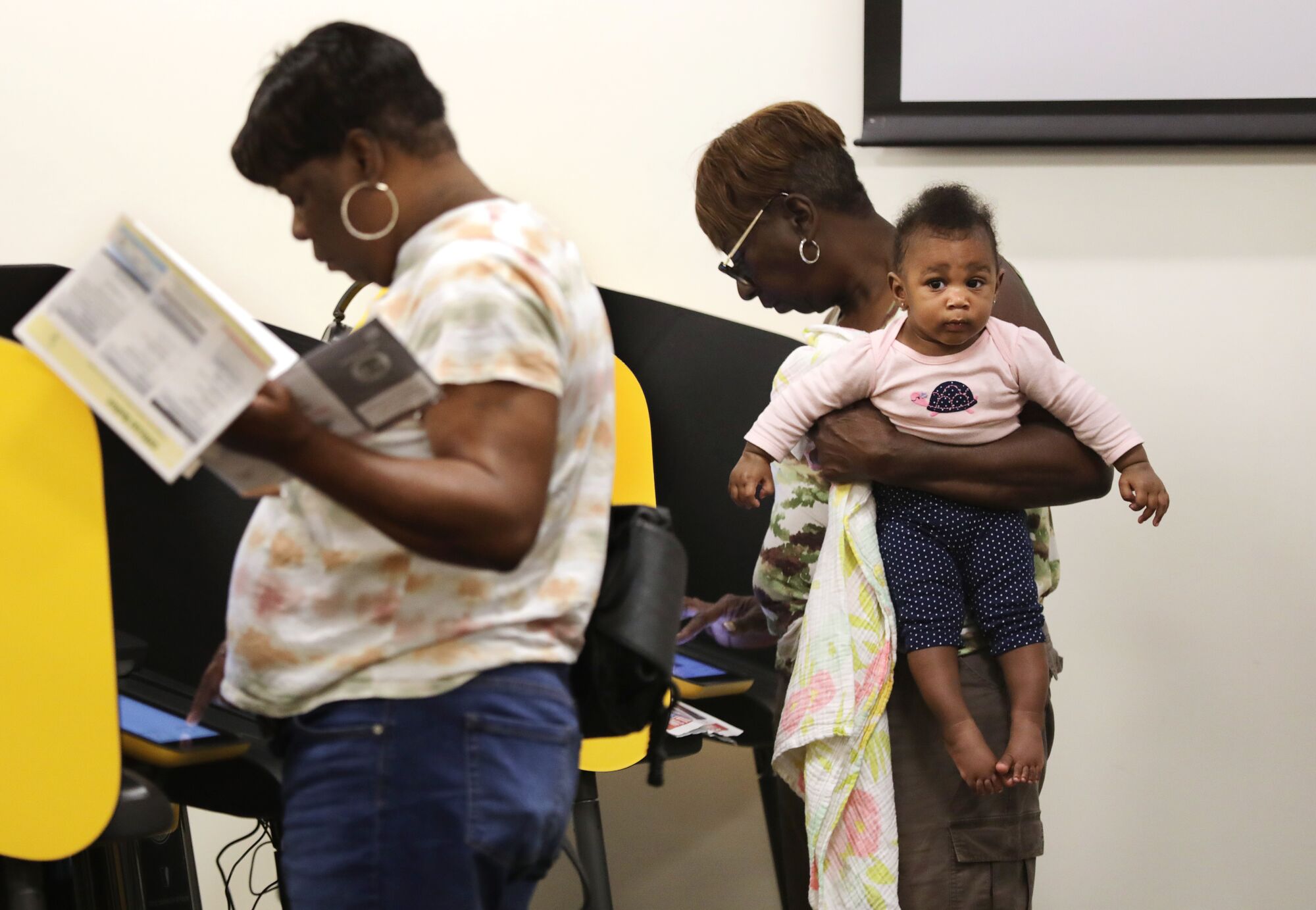 Meltonya Bell, right, carries her granddaughter while voting on Tuesday.