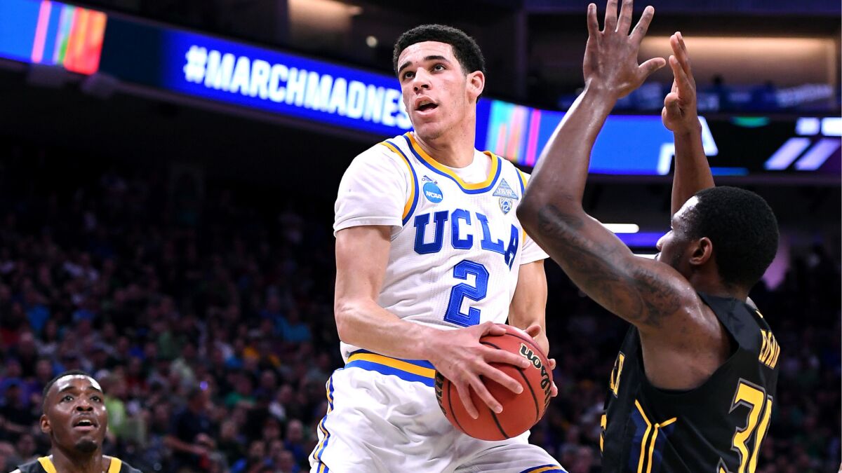 UCLA guard Lonzo Ball powers his way to the basket for a score against Kent State's Kevin Zabo, who was called for a foul on the play during the first half.