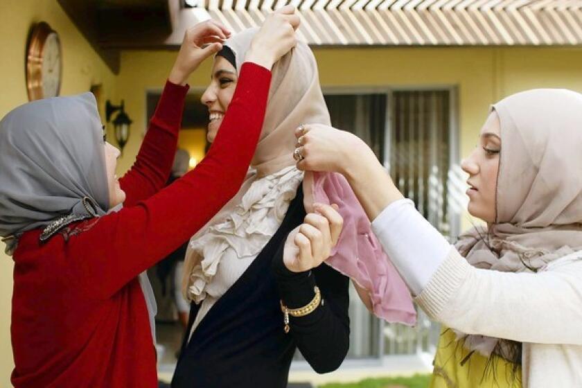 Nora Diab, left, and Marwa Atik adjust a new hijab on friend Marwa Biltagi in the backyard of Atik's home.