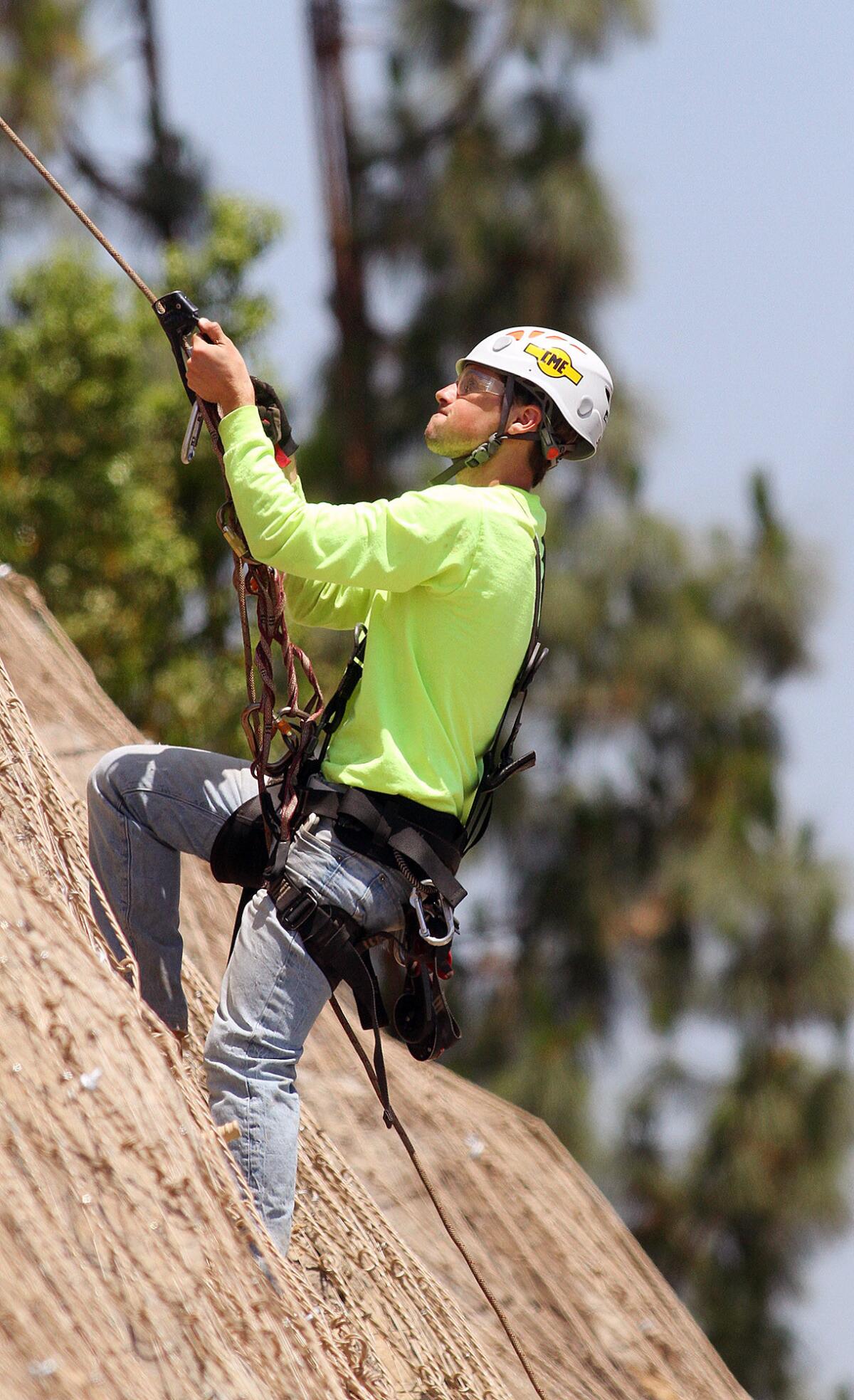 Joseph McElhany, of KANE GeoTech, of Stockton, ascends and descends a rock hillside in La Canada inspecting two layers of wire mesh installed to keep boulders and rocks in place along Foothill Blvd. on Wednesday, June 11, 2014.