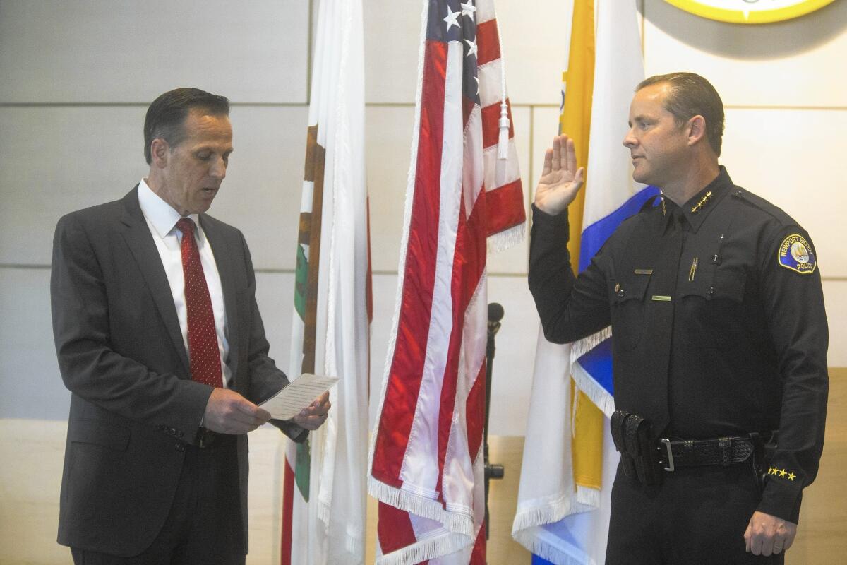 From left, retiring Newport Beach Police Chief Jay Johnson swears in Jon Lewis as the next chief Tuesday afternoon.