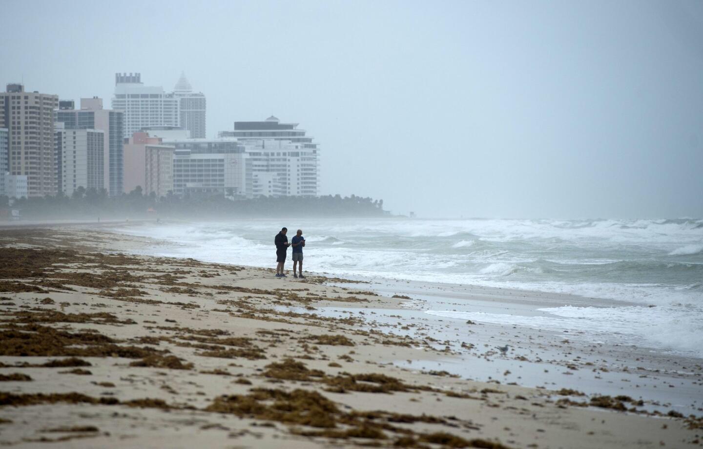 Two men stand on the beach as winds and rain in the outer bands of Hurricane Irma arrive in Miami Beach, Fla., on Sept. 9, 2017.