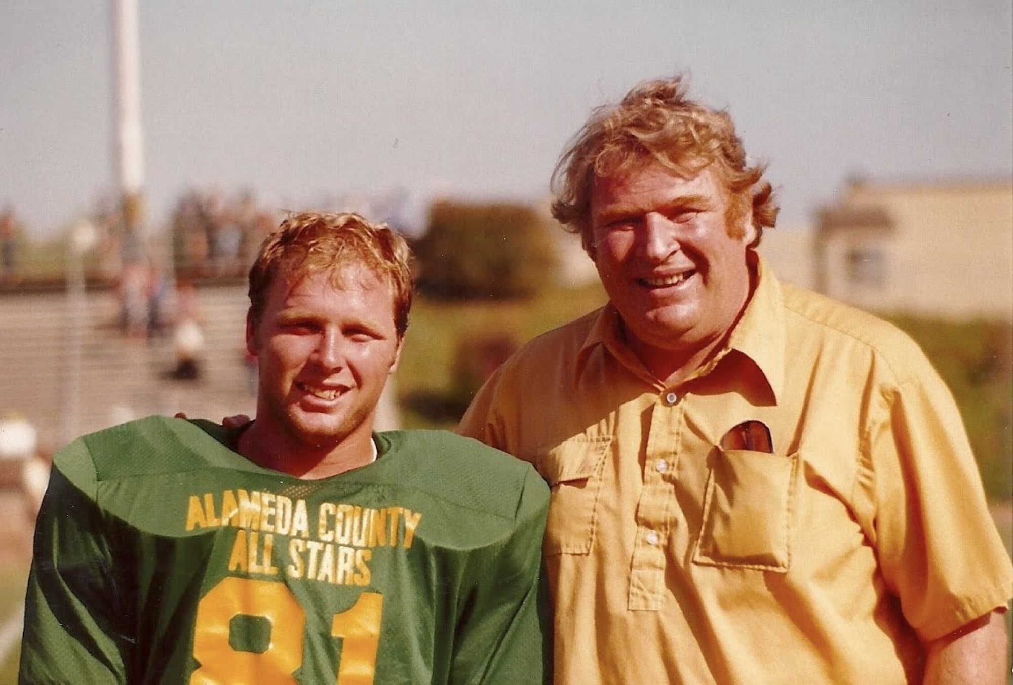 A young Mike Madden in a football jersey stands next to his dad, John Madden