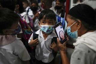 A boy talks to his mother from a smartphone during the opening of classes at the San Juan Elementary School in metro Manila, Philippines on Monday, Aug. 22, 2022. Millions of students wearing face masks streamed back to grade and high schools across the Philippines Monday in their first in-person classes after two years of coronavirus lockdowns that are feared to have worsened one of the world's most alarming illiteracy rates among children. (AP Photo/Aaron Favila)