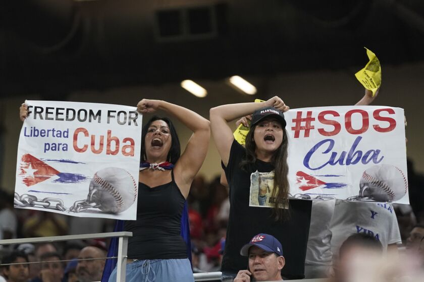 Manifestantes exhiben carteles y corean durante el sexto inning del juego entre Cuba y Estados Unidos en las semifinales del Clásico Mundial de béisbol, el domingo 19 de marzo de 2023, en Miami. (AP Foto/Wilfredo Lee)
