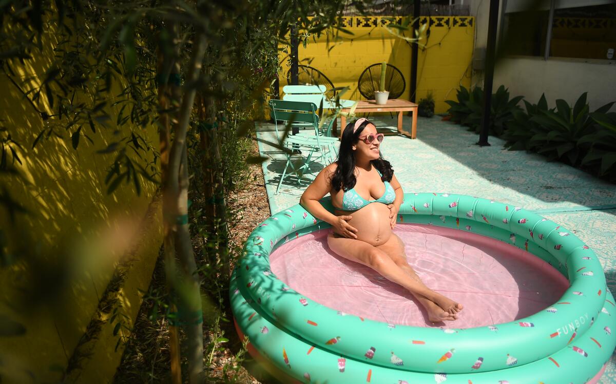 Sofia Gonzalez, nine months pregnant, finds a little relief from the heat in a backyard kiddie pool.