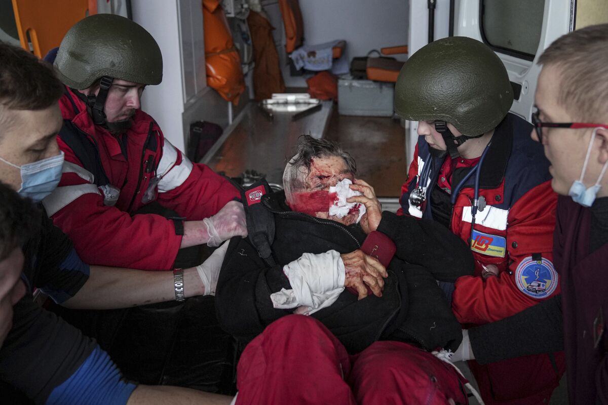 Paramedics surround a person with a bloody face.
