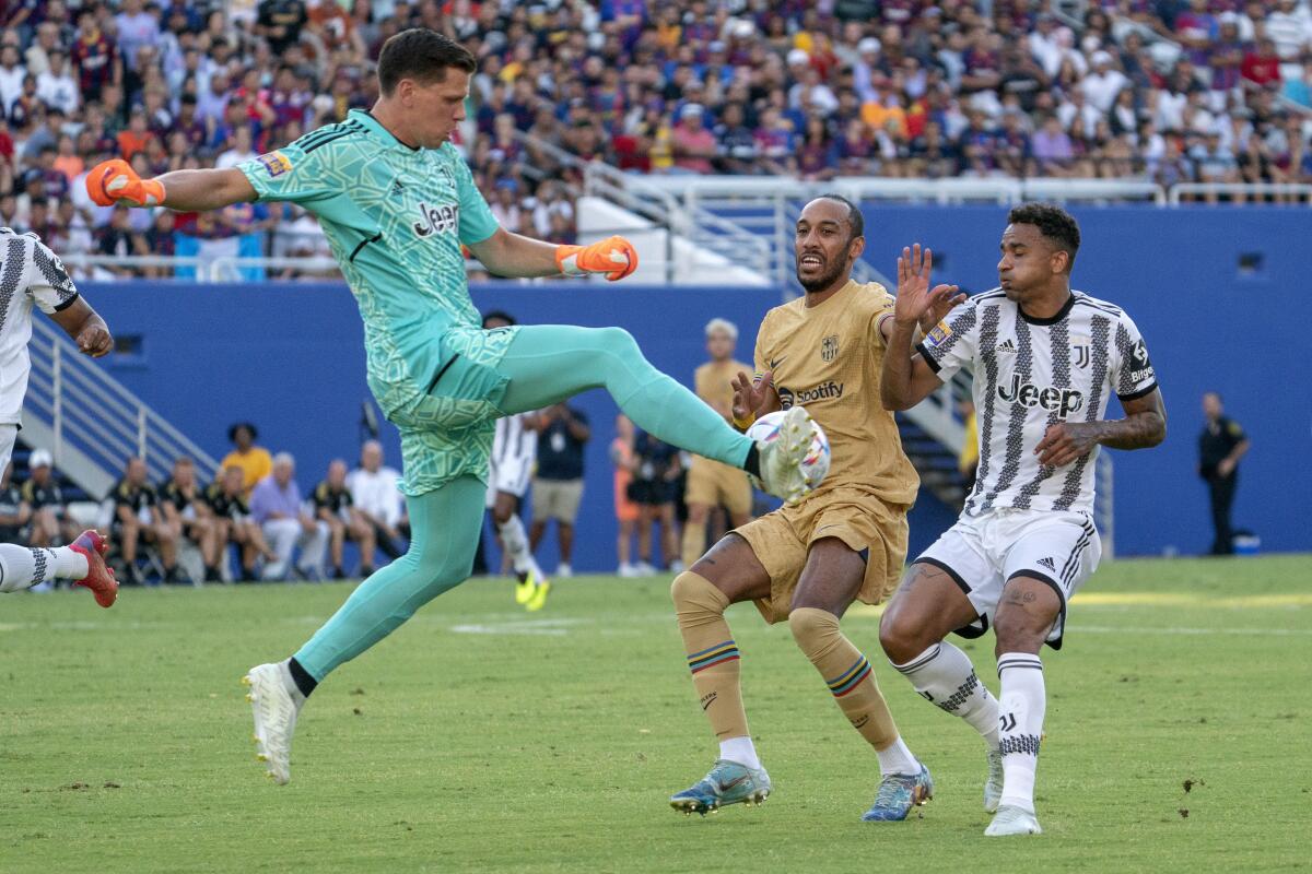 Juventus goalkeeper Wojciech Szczęsny (1) clears the ball away from Barcelona forward Pierre Emeric Aubameyang as Juventus defender Danilo Da Silva applies pressure during the first half of a soccer match at the Cotton Bowl, Tuesday, July 26, 2022 in Dallas. (AP Photo/Jeffrey McWhorter)