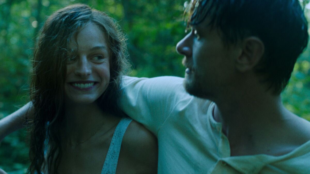 A woman and a man smile at each other in a scene from the movie "Lady Chatterley's Lover."
