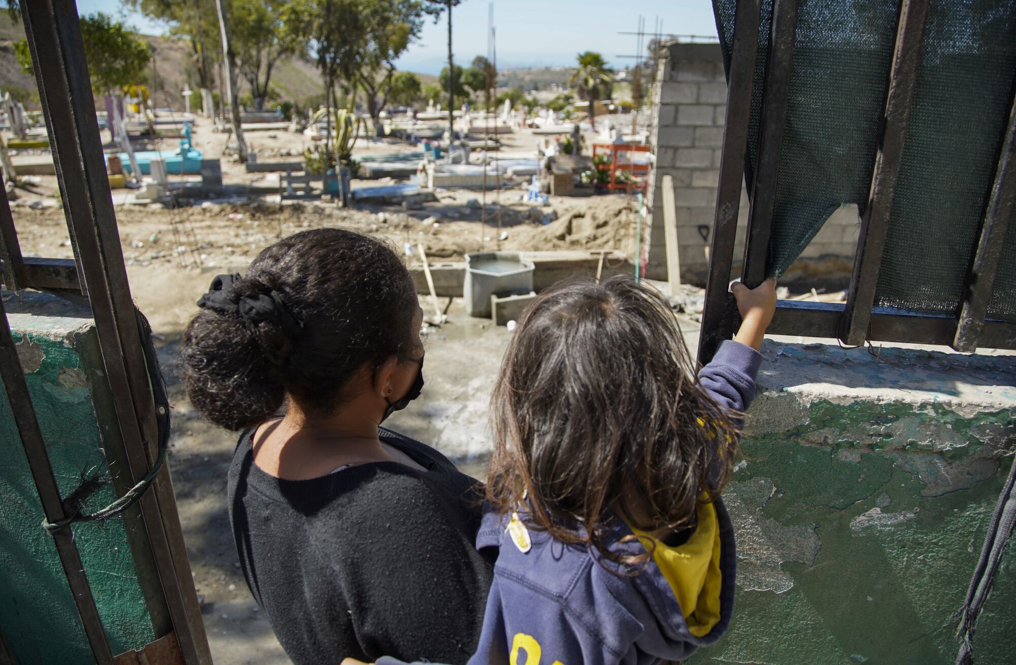 A mother and her child look at a cemetery next to the Agape shelter