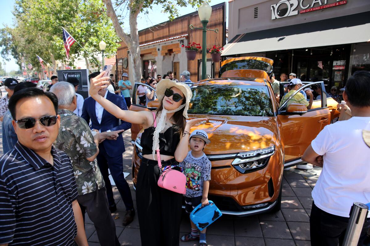 Bui Le Kim Ngoc of Anaheim takes a selfie in front of the VinFast VF8 electric SUV at the VinFast California Showcase event.