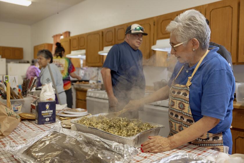 Ethel Humble, an elder at the Springfield United Methodist Church in Okemah, Okla., stirs a steaming tray of wild onions at the church's annual wild onion dinner, April 6, 2024. The church is on the Muscogee Nation's reservation, where the meals using wild onions picked by the community are an annual tradition. (AP Photo/Brittany Bendabout)