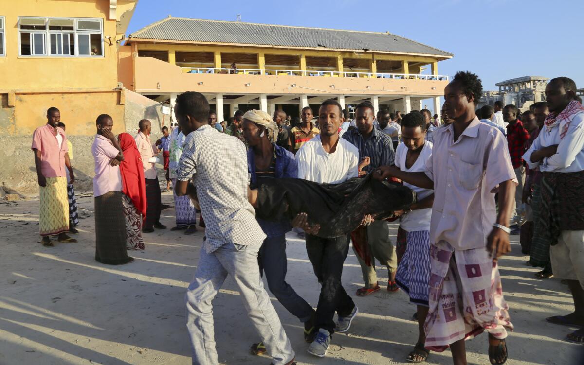 People carry a body Friday after an overnight attack on a beachfront restaurant in Mogadishu, Somalia. The Islamic militant group Shabab claimed responsibility.