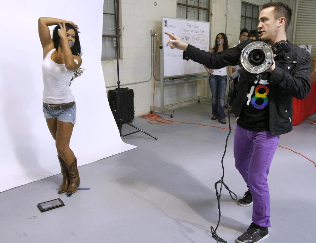 Laura Vol, 30 of Austin Texas, gets direction on posing from celebrity photographer/NOH8 cofounder Adam Bouska during public photo session at the Burbank headquarters on Saturday, Feb. 22, 2014.