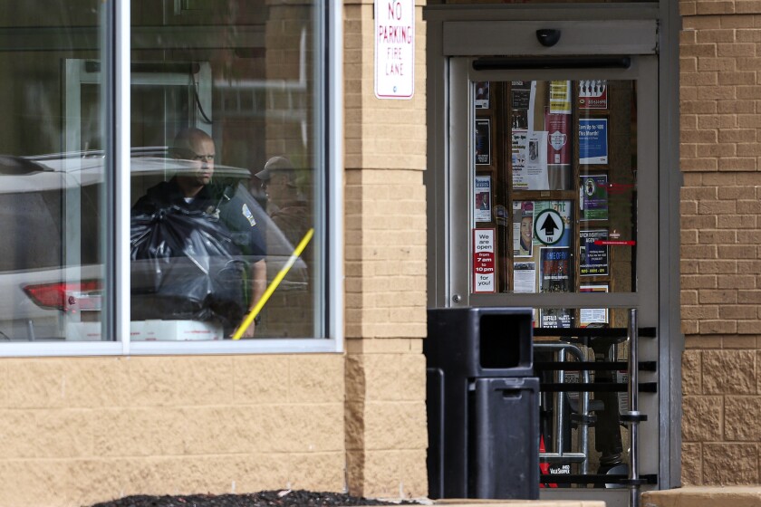 A police officer looks out a store window as authorities investigate a shooting at the supermarket, Saturday.