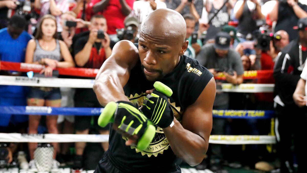 Floyd Mayweather Jr. shadow boxes with weights in his hands during a workout for the media.