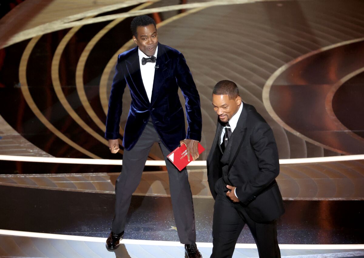 Chris Rock reacts to being slapped as Will Smith leaves the stage.
