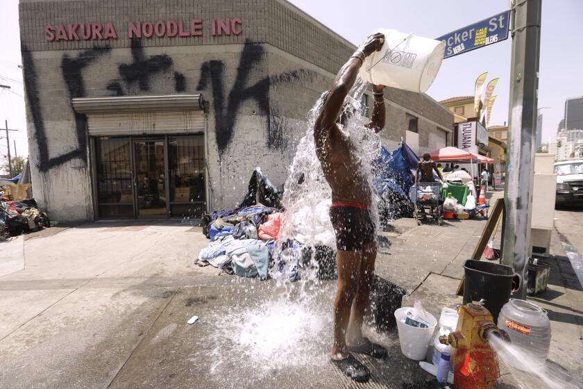 LOS ANGELES, CA - AUGUST 12, 2021 - Dennis Johnson, 60, washes himself with a bucket of water, collected from a nearby fire hydrant, at the corner of Crocker and 7th Streets in Skid Row in downtown Los Angeles on August 12, 2021. Temperatures reached 92 degrees in downtown Los Angeles on this day. Johnson, who has been living in a tent on the street for the past 4 months, says when it gets hot he just lifts the tarp over his encampment. "Mother Nature gives us what we need. What we need is some good rain," said Johnson. Seven men and women were found dead last year from heat-related causes on sidewalks, in cars, and on bus benches in LA. Most had been living on the streets, and three were found within hours of each other in the Skid Row area in 2020 according to the Los Angeles County Department of Medical Examiner-Coroner. (Genaro Molina / Los Angeles Times)